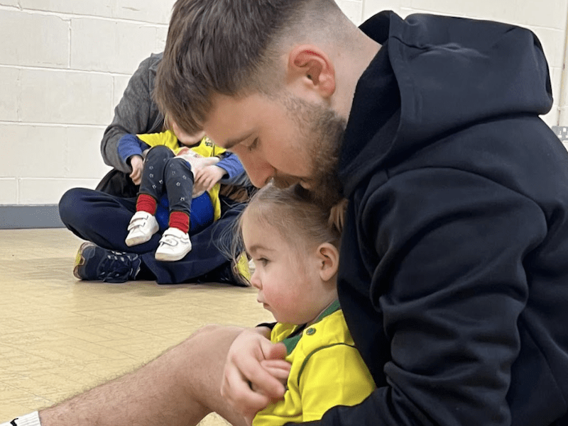 Baby learning and development. Image shows a dad holding his daughter during a socatots class.