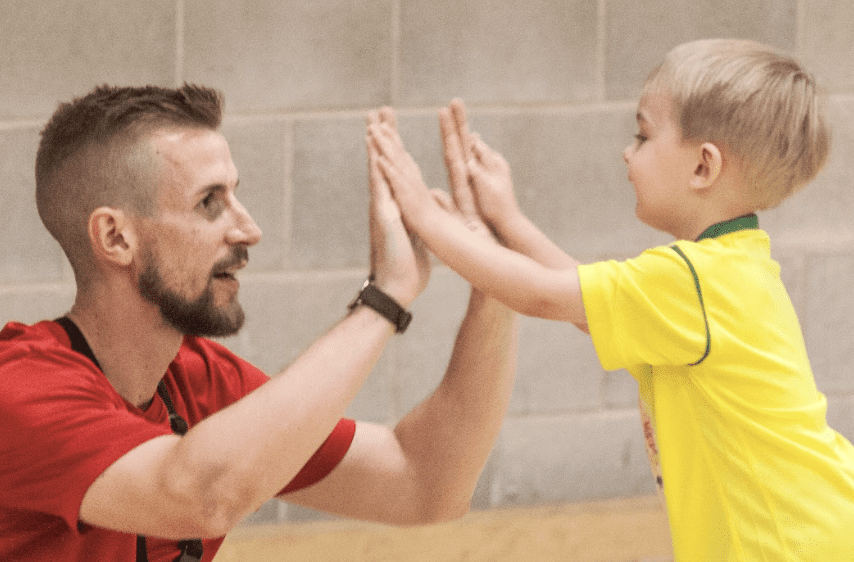 Football coach for toddlers. Image shows a toddler high- fiving a Socatots football coach.