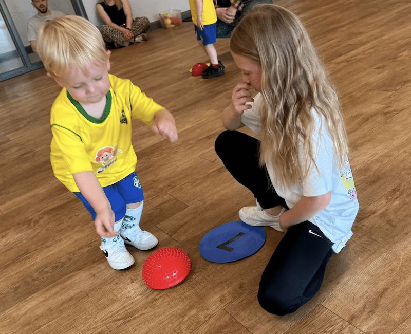 Toddler play. Image shows a toddler and a sibling playing at a Socatots class.
